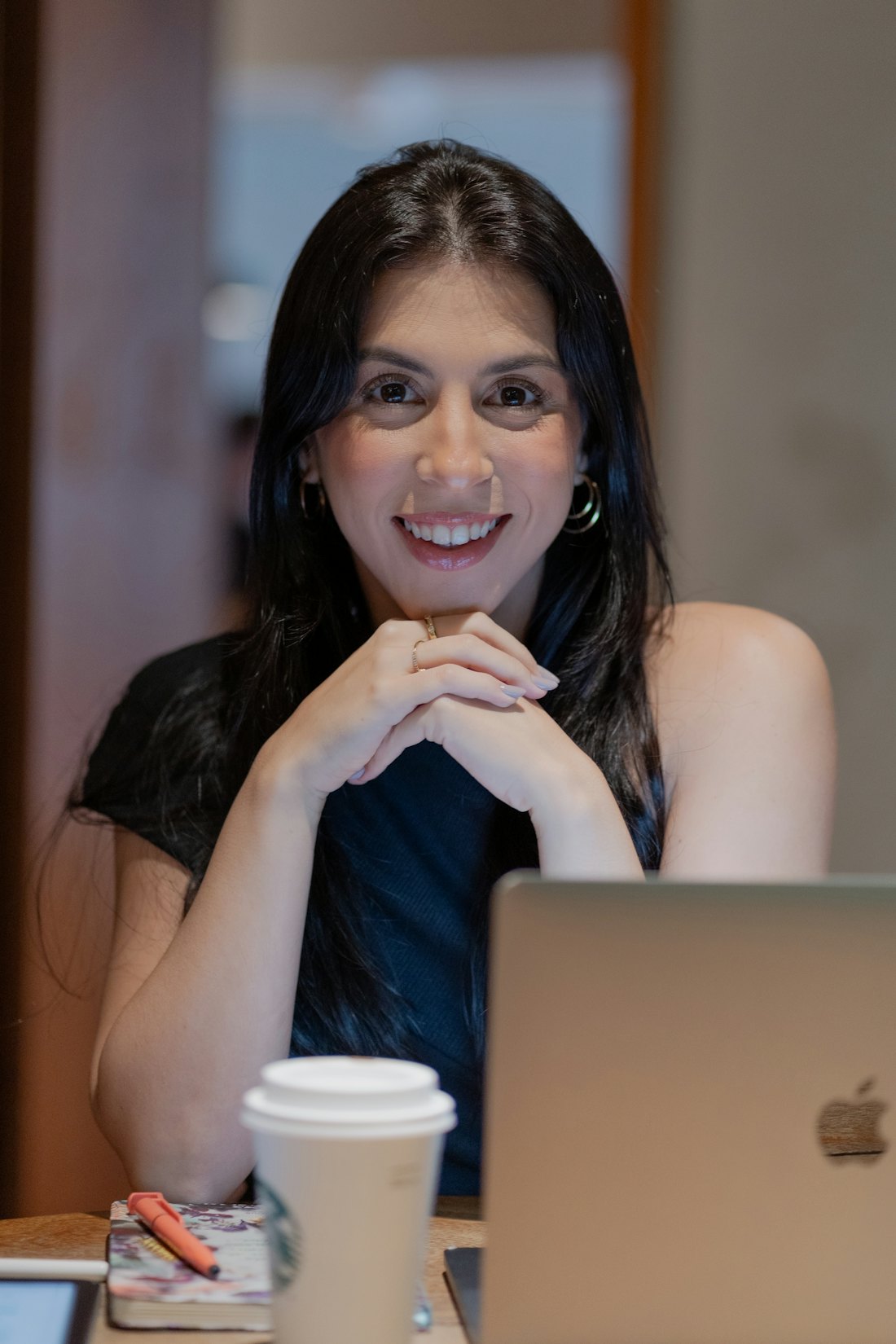 A young woman smiling at her laptop with a coffee