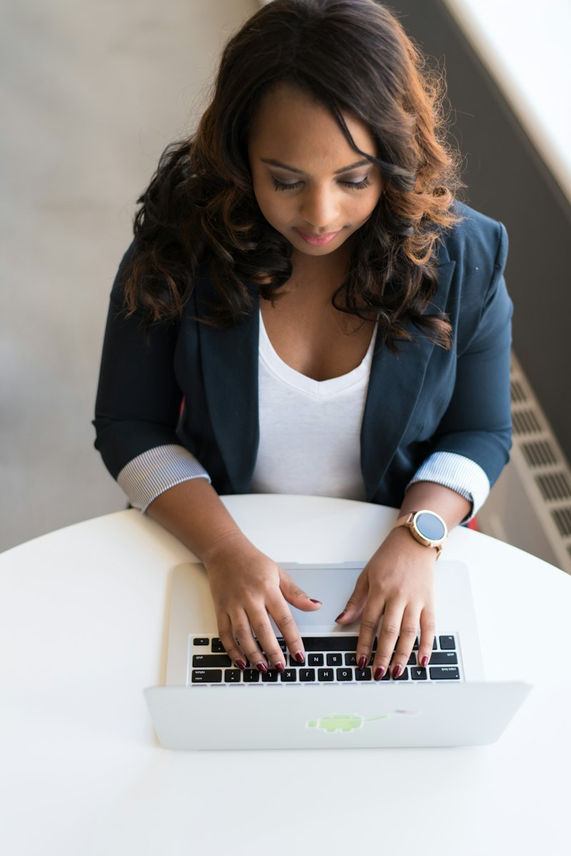 A young woman in a blazer typing on her laptop